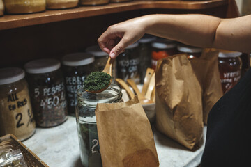 woman choosing spices sold by weight in organic shop