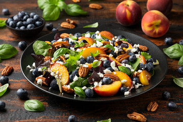 Peach, blueberry salad with vegetables, feta cheese and pecan nuts. Healthy summer food