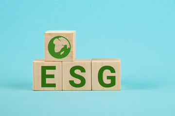 ESG concept of environmental, social and governance. ESG Words on a wood cubes. Wooden cube with abbreviation ESG on blue background