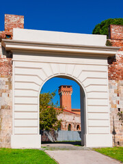 Fototapeta na wymiar Medieval tower seen through Pisa ancient walls gate