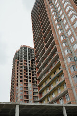 Fototapeta premium Below shot of blocks of flats or highrise condos built up by modern architectural project in central region of city with grey sky above