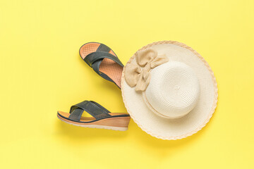 A large women's hat and summer mesh shoes on a yellow background. The minimum concept of summer...