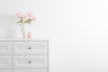 pink peonies in ceramic white vase in white interior