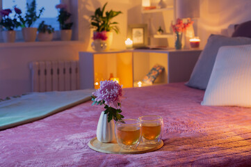 cozy bedroom in  evening with flowers and tea