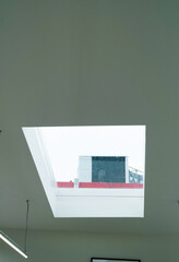 Window on ceiling with cloudy sky in modern room.