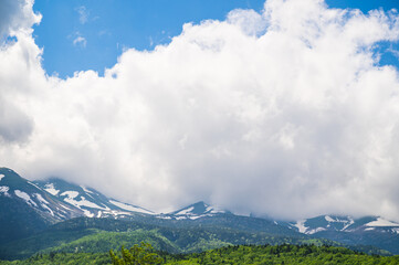 残雪残る山と大きな白い雲 - obrazy, fototapety, plakaty