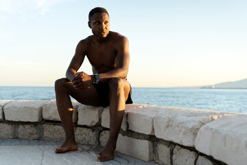 Fototapeta na wymiar Handsome and confident young african american man sitting on the beach