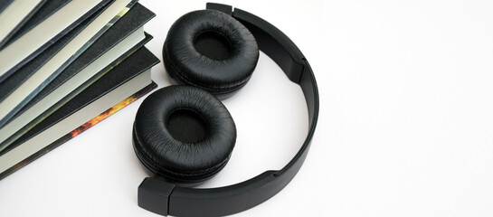 Black headphones with stack of books on light background.