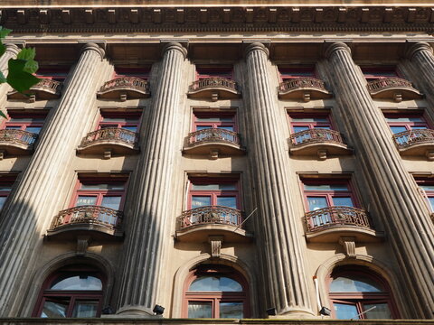 Facade of old building in center of Bucharest with columns, windows and arched balconies with wrought iron and decorations