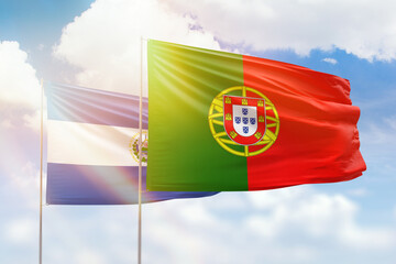 Sunny blue sky and flags of portugal and el salvador