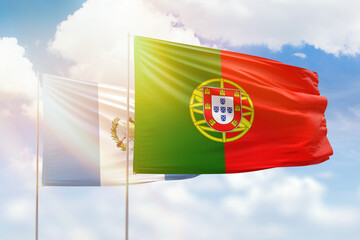 Sunny blue sky and flags of portugal and guatemala