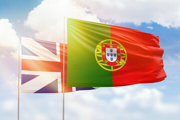 Sunny blue sky and flags of portugal and great britain