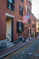 Acorn Street Beacon Hill house during fall harvest with American Flag and cobblestone alley in Boston, Massachusetts.