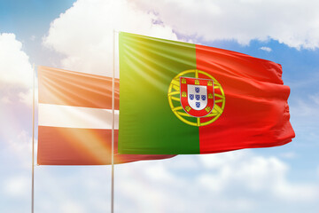 Sunny blue sky and flags of portugal and latvia