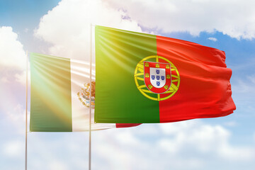 Sunny blue sky and flags of portugal and mexico
