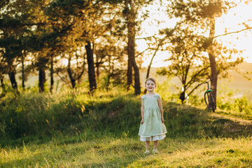 Little girl in a field with hay rolls at sunset
