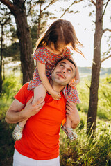 Family time. Father and little daughter together. He tickles her, and she laughs. They are dressed in sweaters. Leisure.