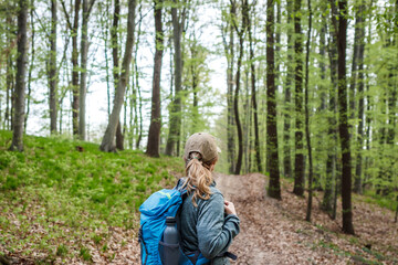 Hiking in forest. Woman with backpack trekking on footpath in woodland