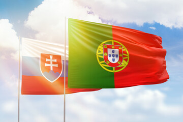 Sunny blue sky and flags of portugal and slovakia