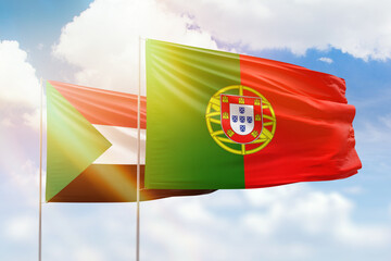 Sunny blue sky and flags of portugal and sudan
