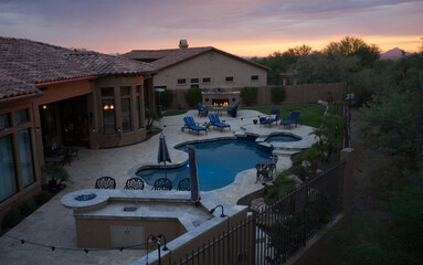 an aerial view of a desert landscaped house in Arizona featuring a travertine tiled pool deck and outdoor kitchen.