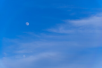 abstract background of fluffy clouds and the moon on a blue evening sky
