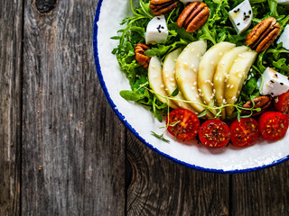 Fresh salad - goat cheese, pear and vegetables on wooden table
