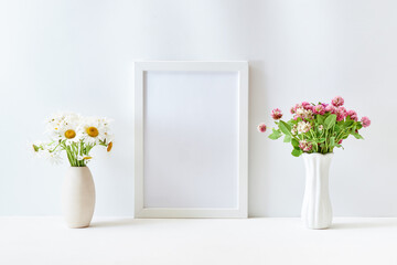 Home interior with decor elements. Mockup with a white frame and wildflowers in a vase on a light background