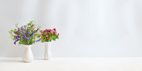 Wildflowers in a vase on a white table. Mock up for displaying works
