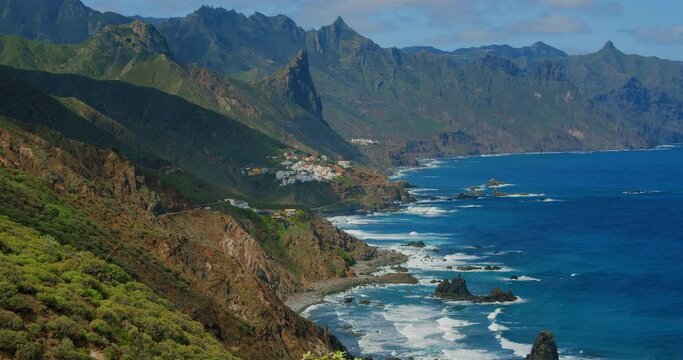Atlantic Ocean and cute town or village Almaciga. Playa del Roque de las Bodegas, north of Tenerife, Spain. Green coastline.