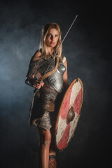 Warrior woman in the armor and with the sword and wooden shield concept.