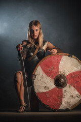 Fototapeta na wymiar Warrior woman in the armor and with the sword and wooden shield concept.