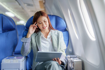 Travel, Portrait of an Asian business woman using tablet computer to plan while on a plane between...