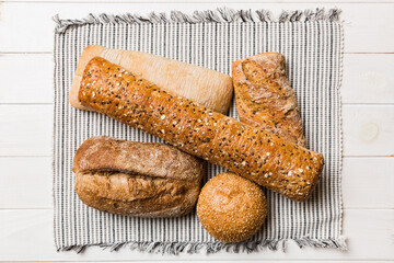Assortment of freshly baked bread with napkin on rustic table top view. Healthy unleavened bread. French bread