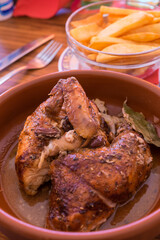 Pollo asado en un cuenco de barro y patatas fritas