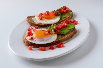 Two sandwiches with cheese, fried egg and avocado for breakfast. Mexican molletes. 