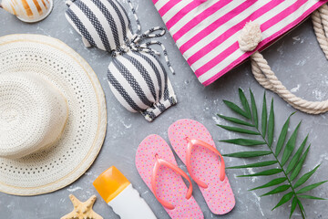 Woman swimwear and beach accessories flat lay top view on colored background Summer travel concept. bikini swimsuit, straw hat and seasheels. Copy space Top view