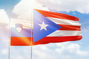 Sunny blue sky and flags of puerto rico and slovenia