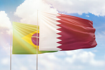 Sunny blue sky and flags of qatar and brazil