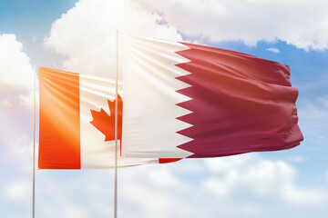 Sunny blue sky and flags of qatar and canada