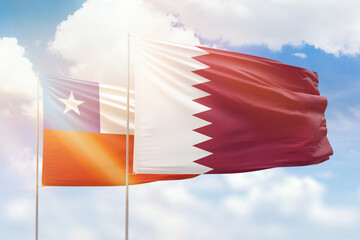 Sunny blue sky and flags of qatar and chile