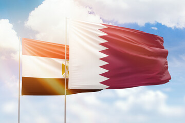 Sunny blue sky and flags of qatar and egypt
