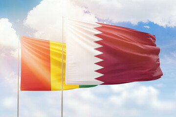 Sunny blue sky and flags of qatar and guinea