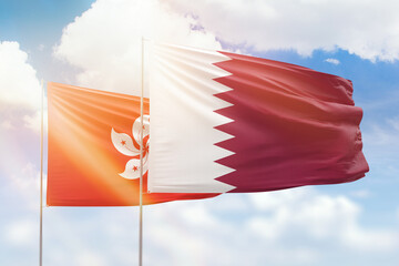 Sunny blue sky and flags of qatar and hong kong