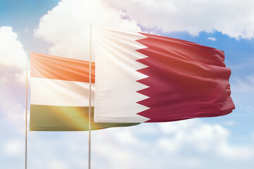 Sunny blue sky and flags of qatar and hungary