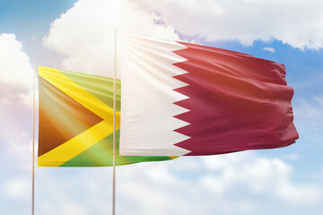 Sunny blue sky and flags of qatar and jamaica