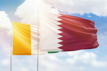 Sunny blue sky and flags of qatar and ivory coast