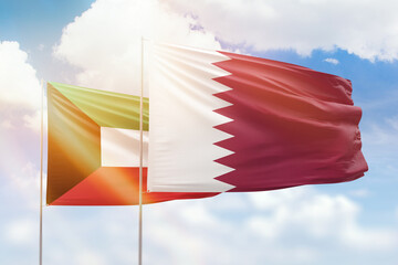Sunny blue sky and flags of qatar and kuwait