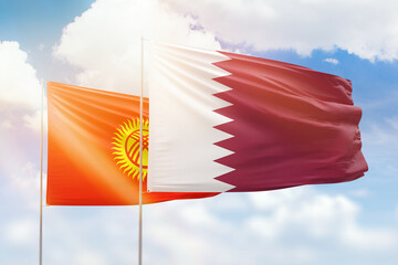 Sunny blue sky and flags of qatar and kyrgyzstan