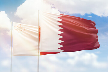 Sunny blue sky and flags of qatar and malta